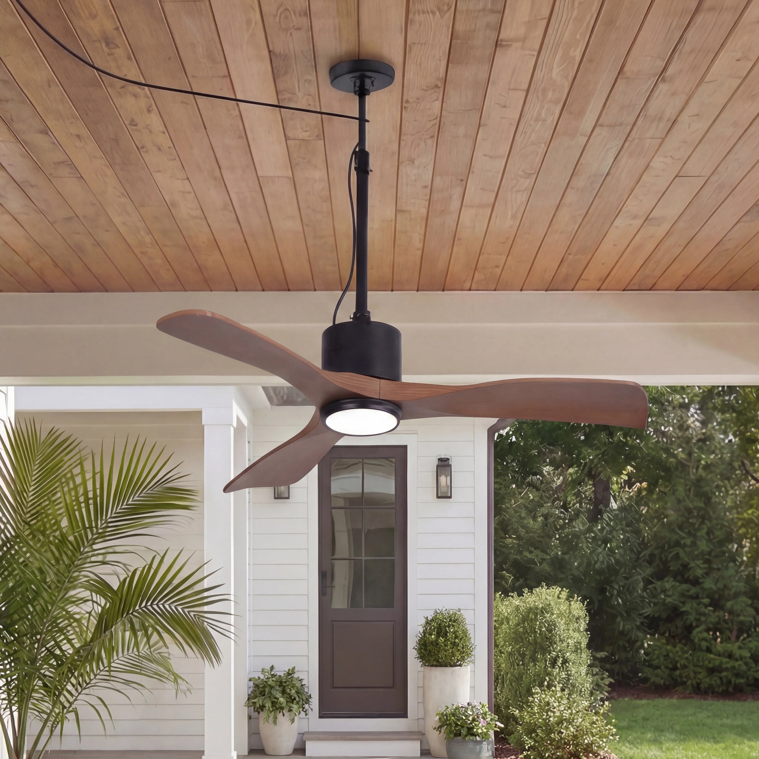 Modern wood ceiling fan with LED light on covered porch, white house background, outdoor setting