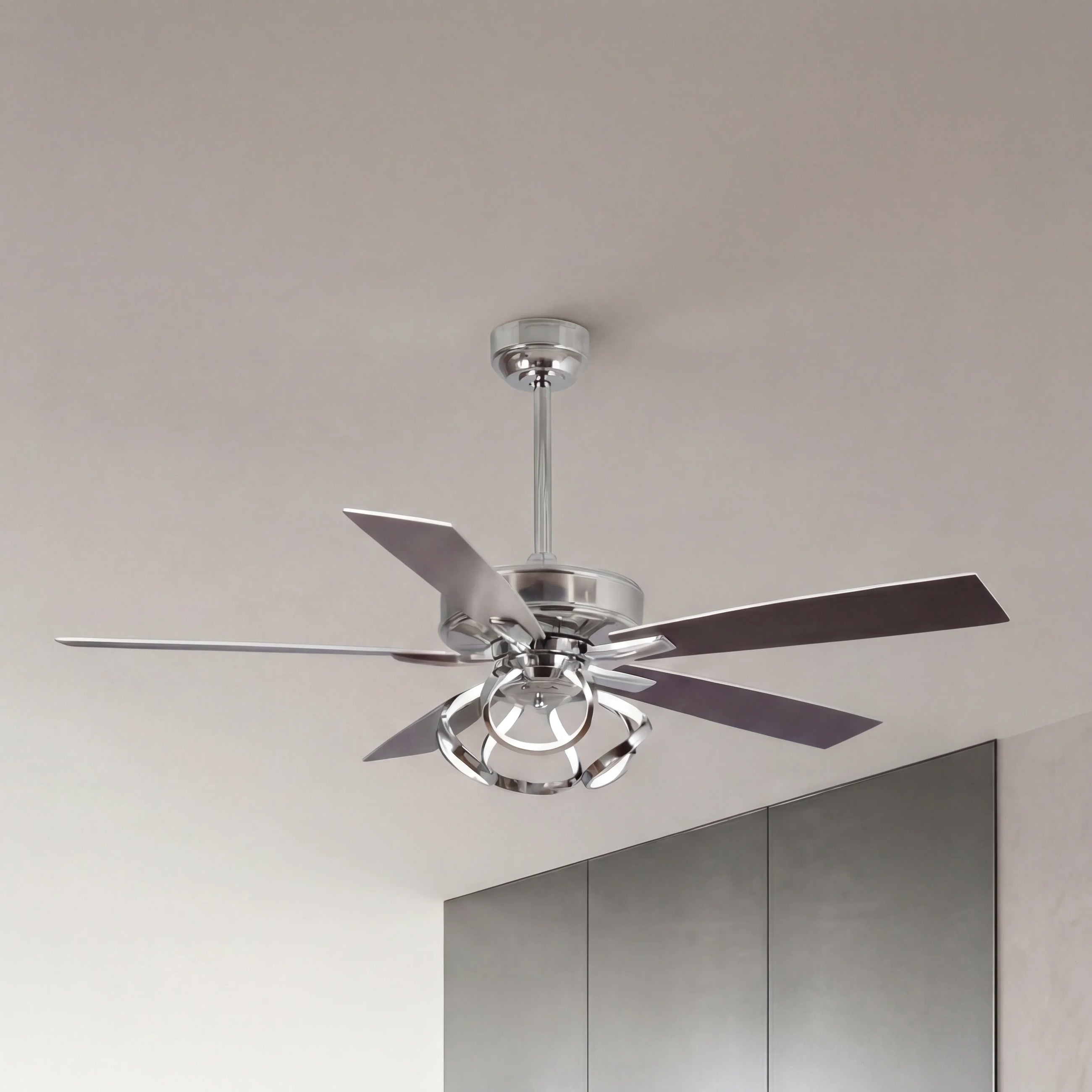Modern silver ceiling fan with sleek blades and integrated light fixture in a minimalist room