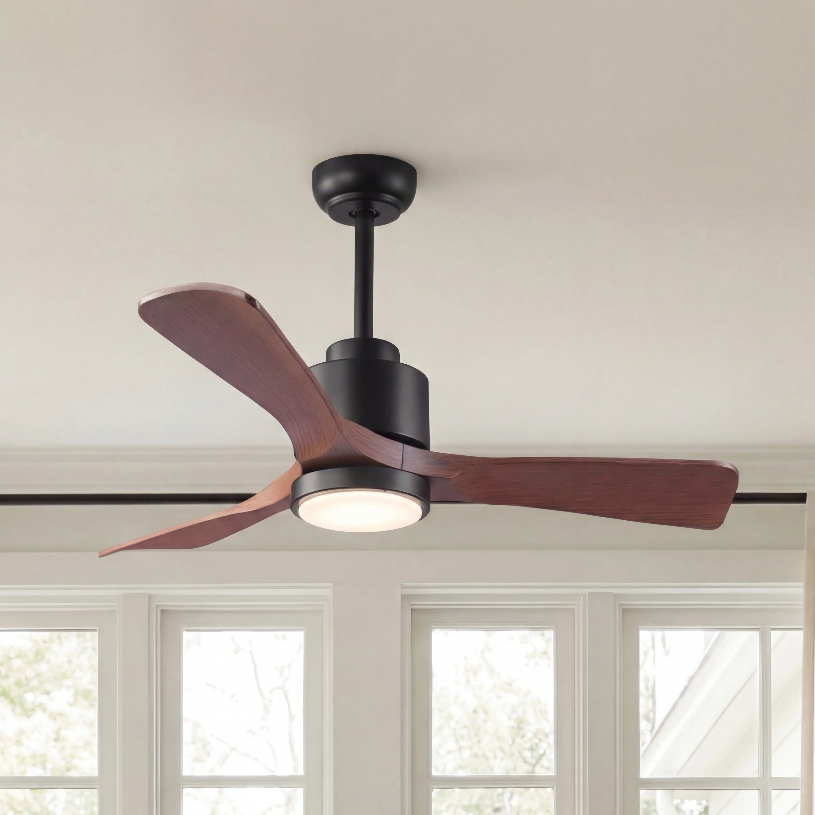 Modern ceiling fan with wood blades and integrated LED light in a bright room