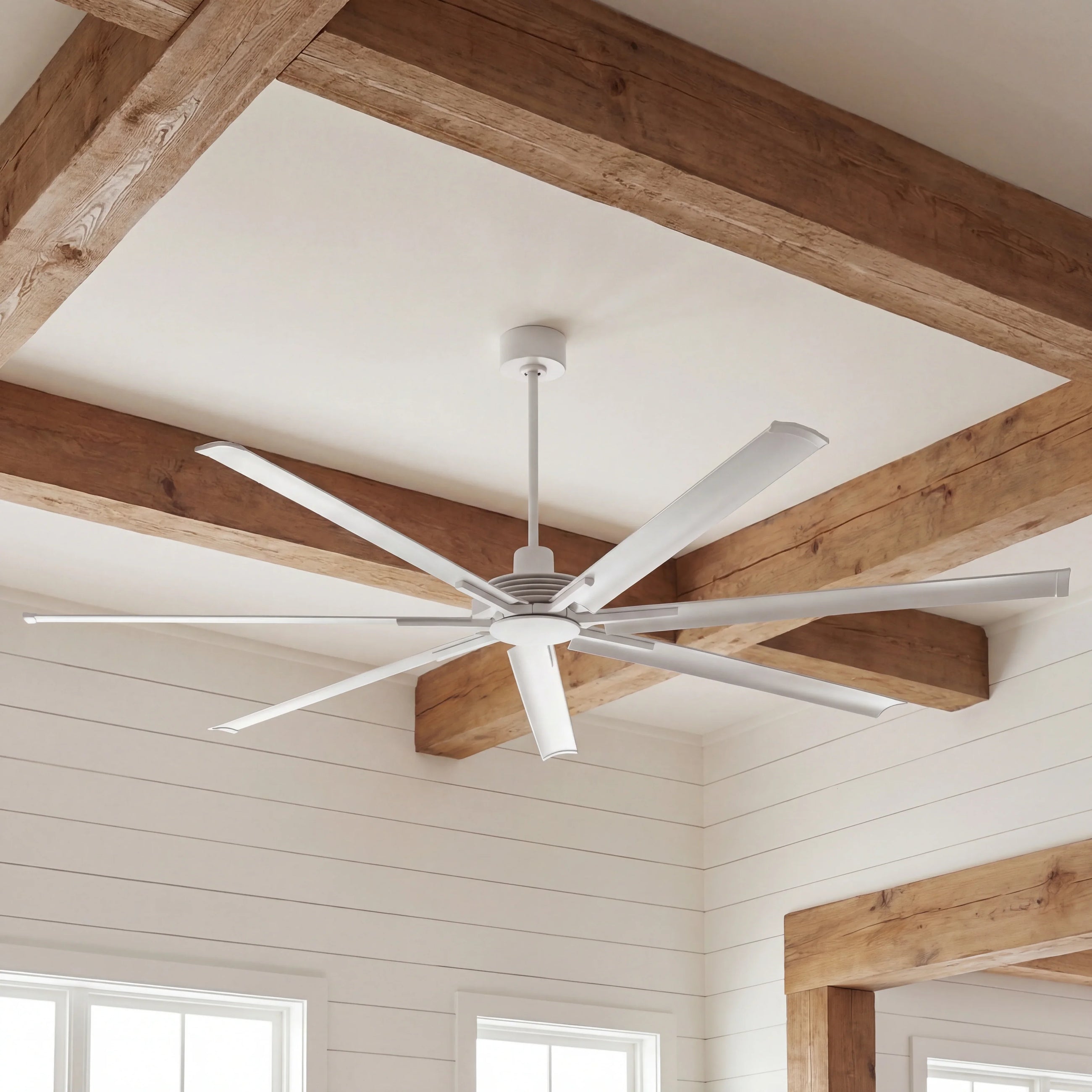 Modern white ceiling fan with multiple blades in a room with exposed wooden beams and shiplap walls