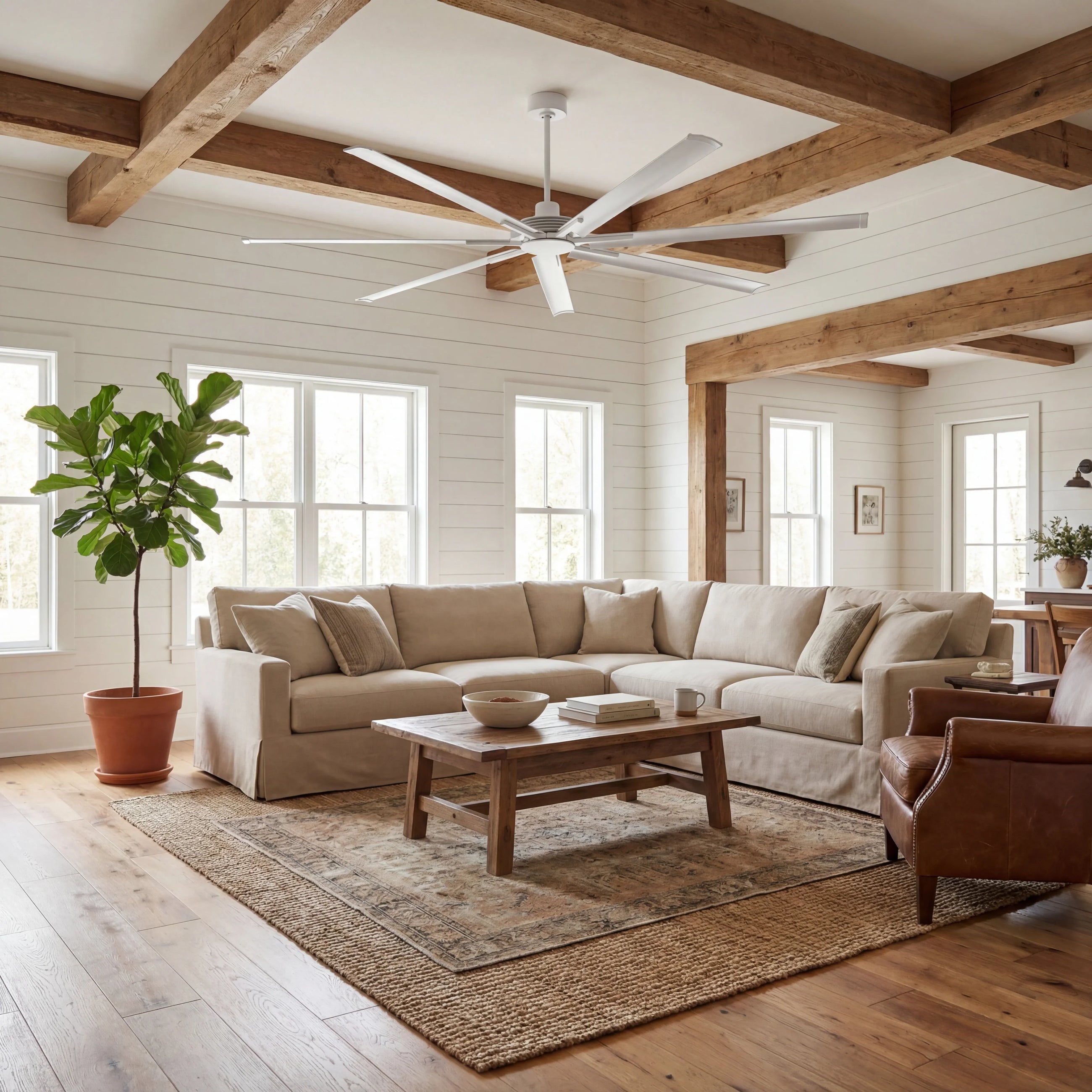 Modern white ceiling fan in a cozy living room with wood beams and neutral furniture.