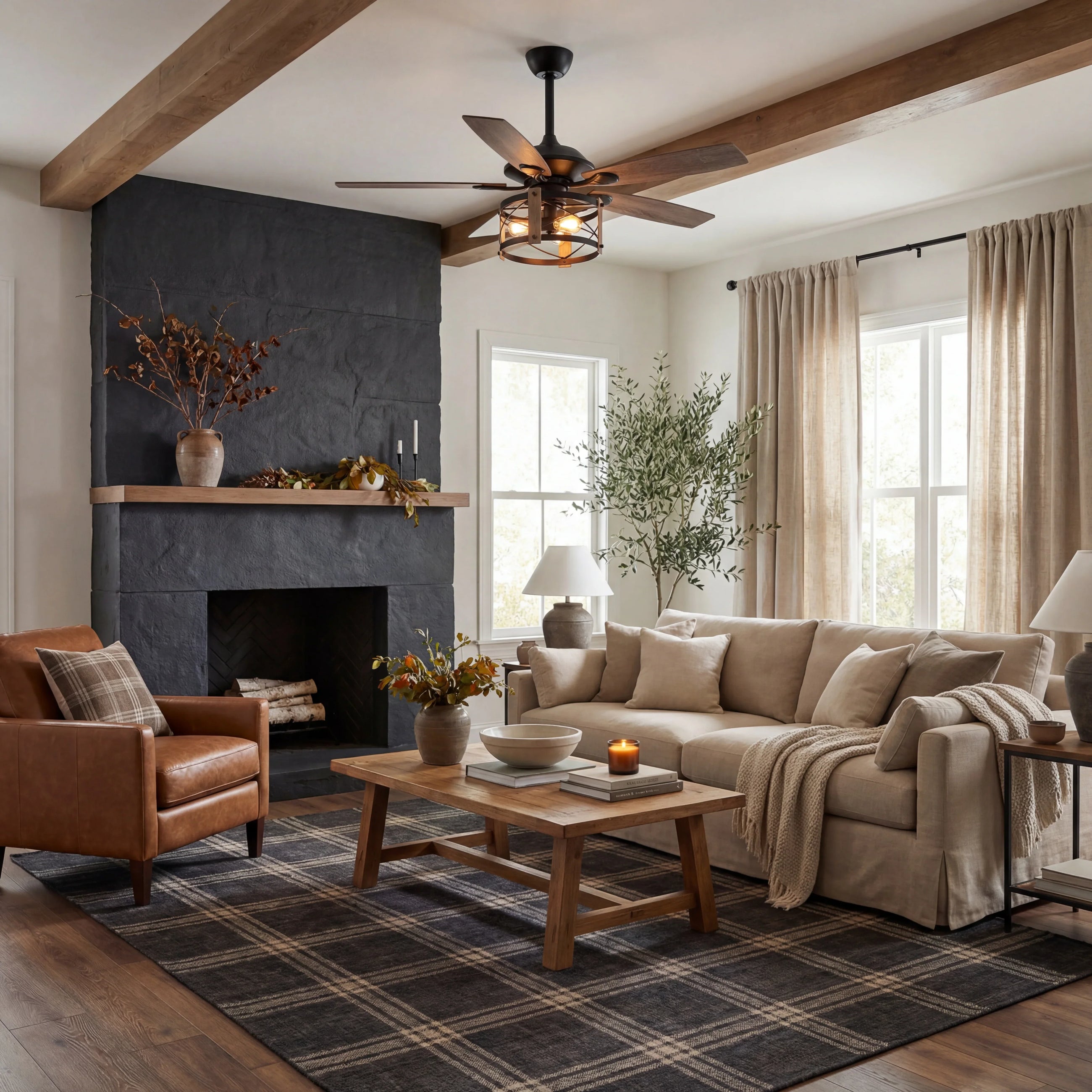 Modern living room with wood ceiling fan, neutral sofa, leather armchair, and cozy fireplace.