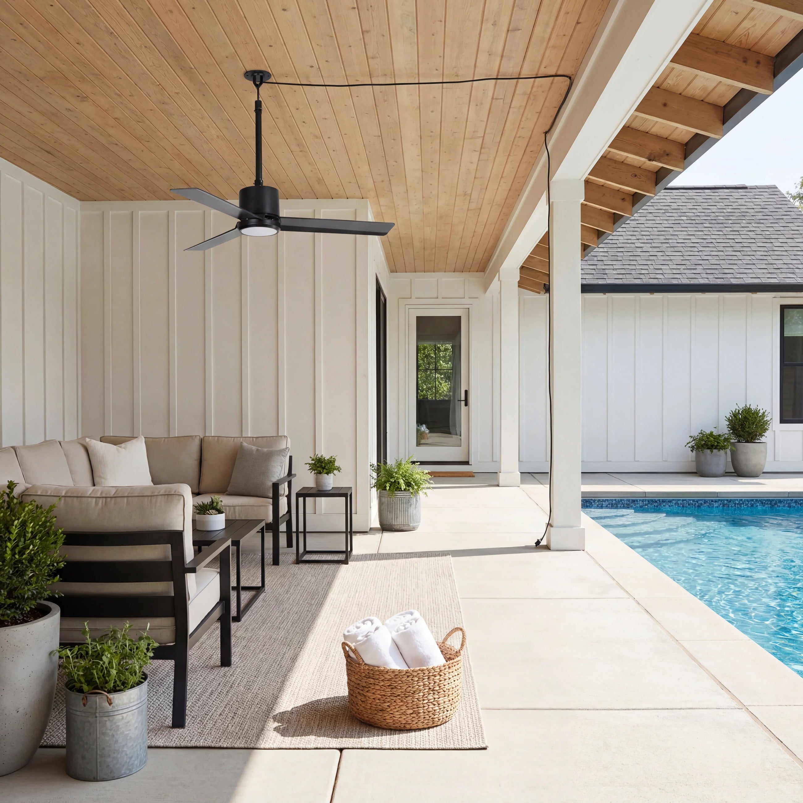 Modern outdoor patio with black ceiling fan, cozy sectional sofa, and poolside seating area