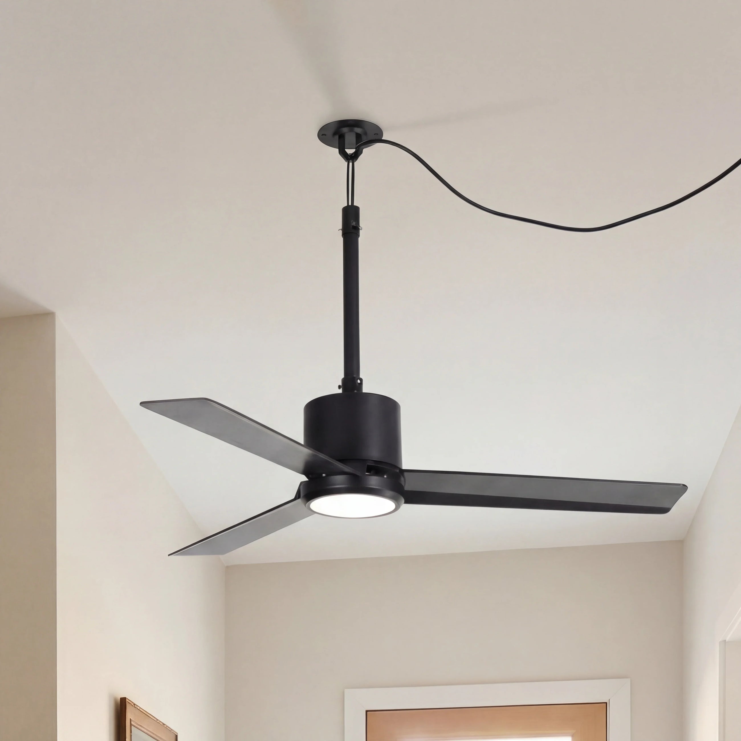 Modern black ceiling fan with integrated LED light in a bright, minimalist room