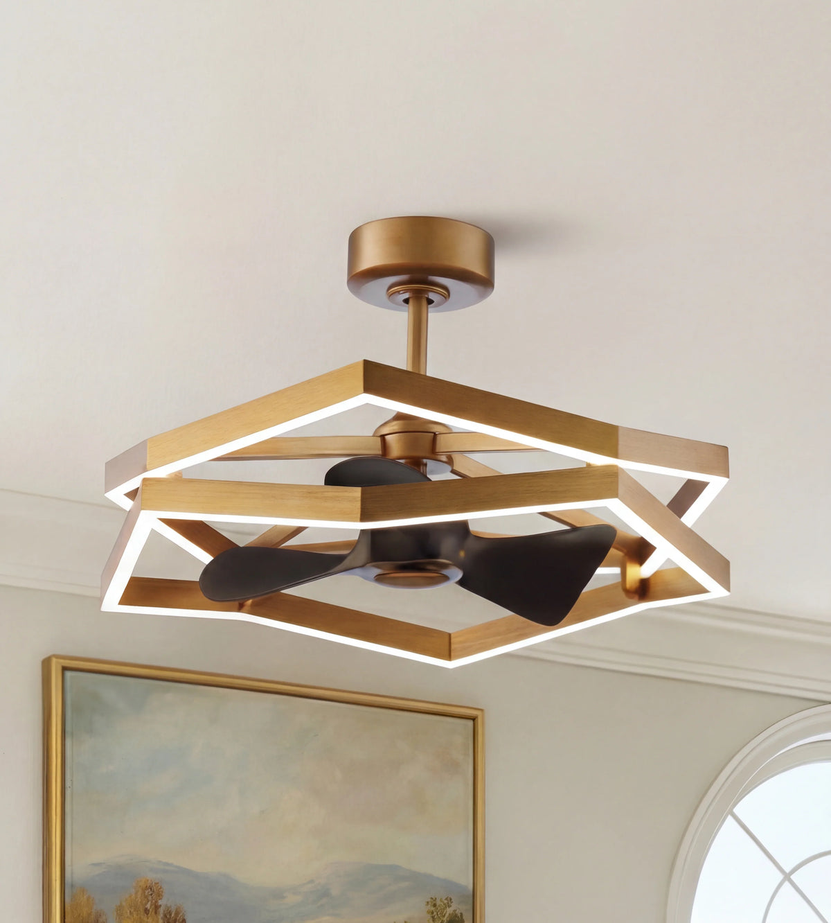 Modern gold ceiling fan with geometric LED frame and black blades in a bright room