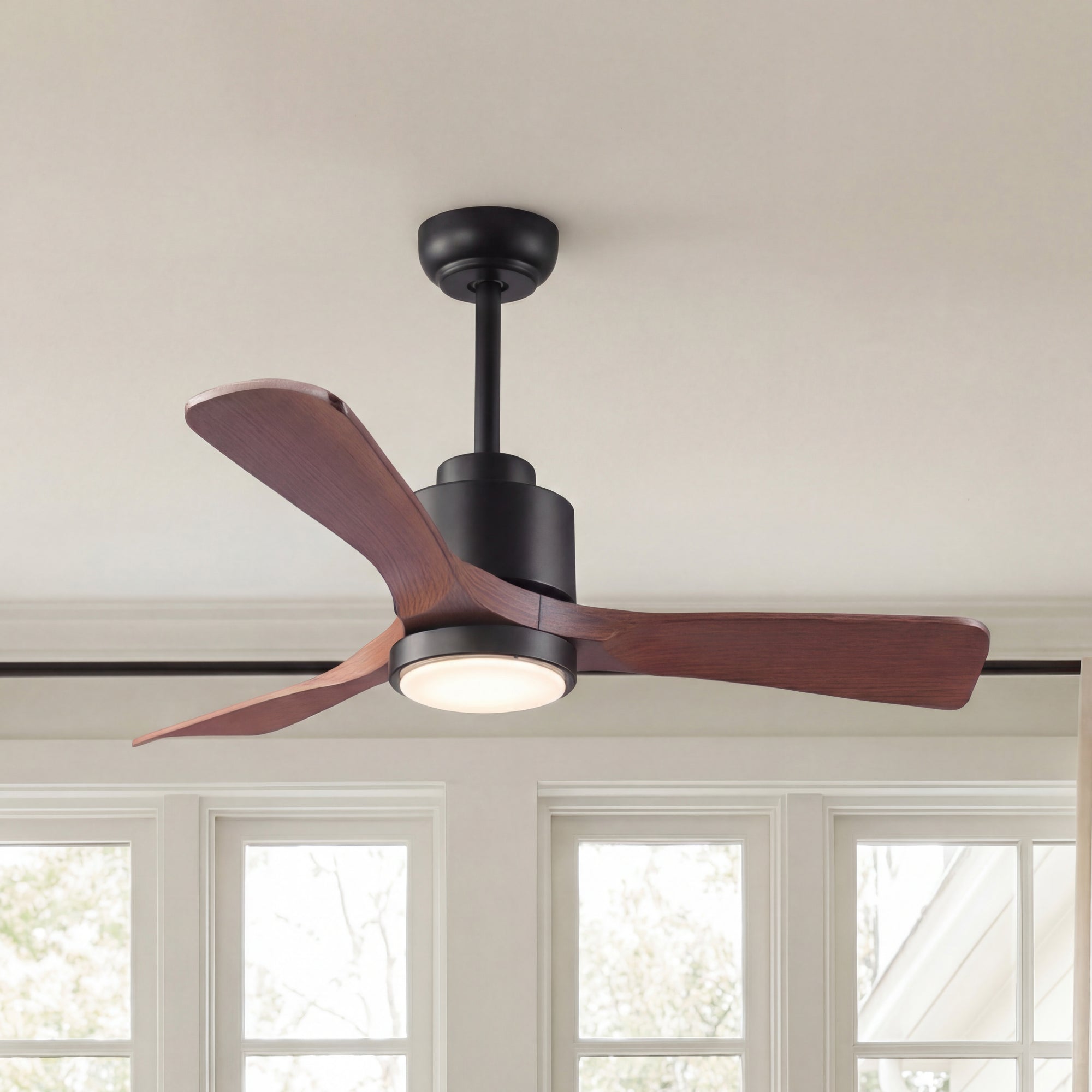 Modern ceiling fan with wood blades and integrated LED light in a bright room