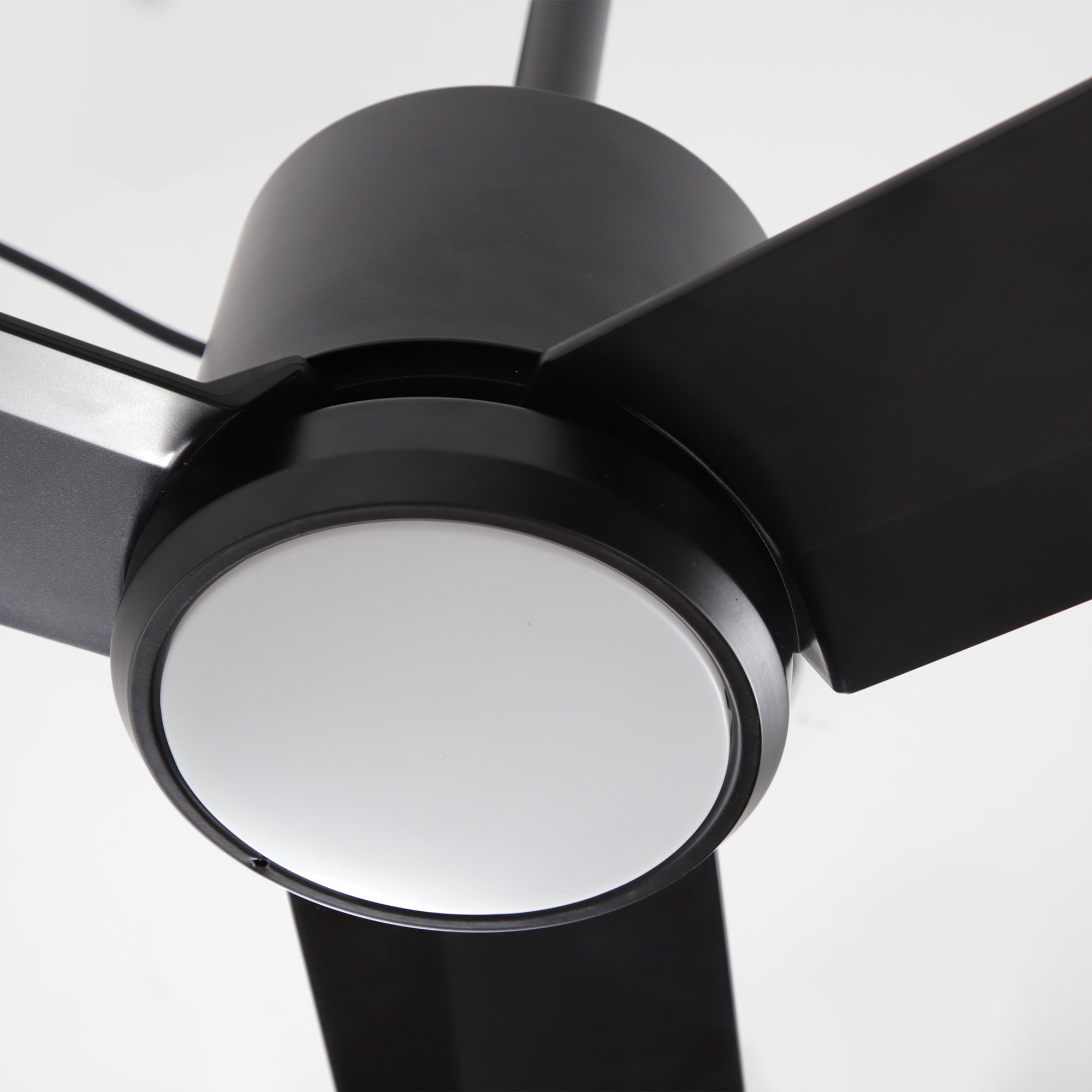 Modern black ceiling fan with three blades and integrated LED light, close-up view.