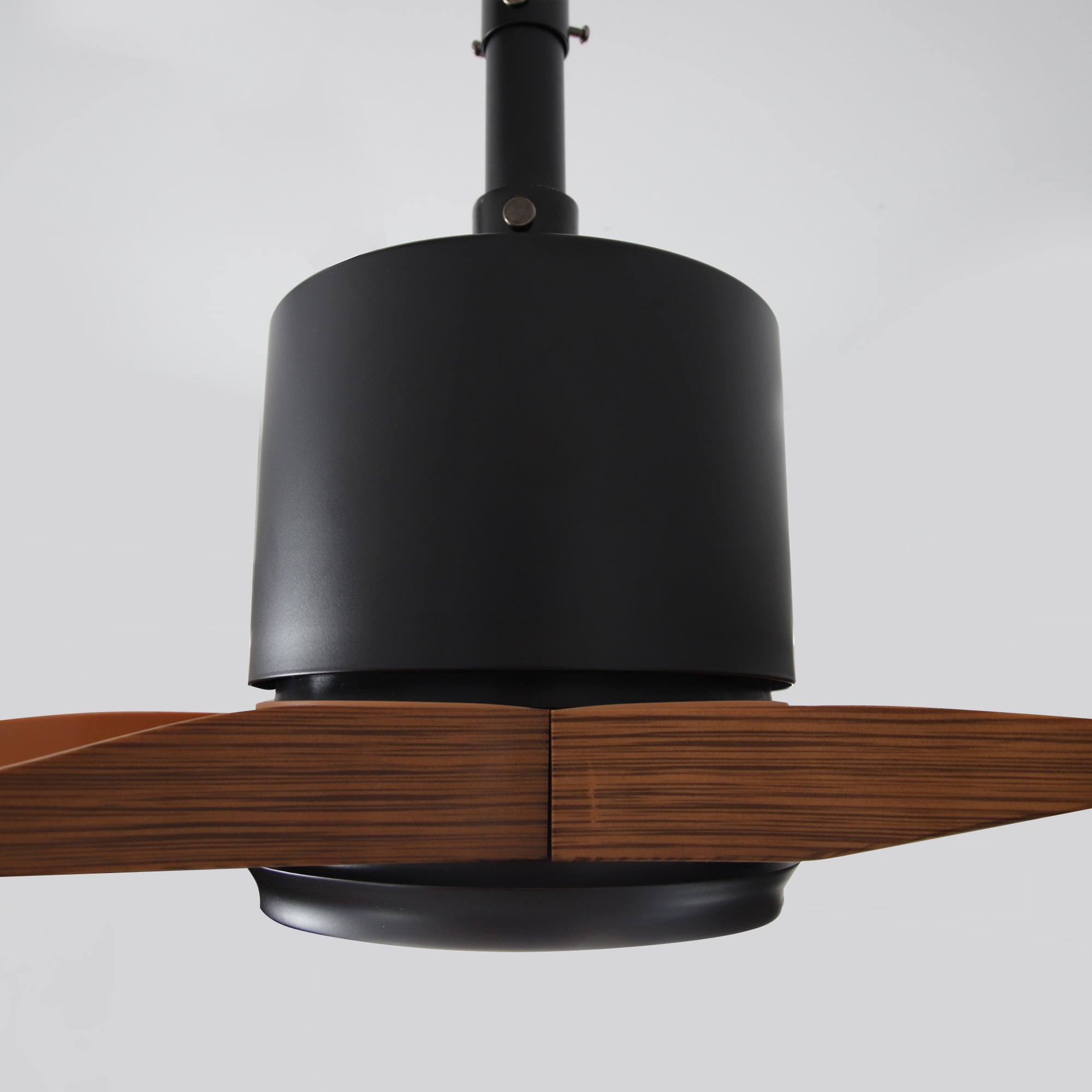 Modern ceiling fan with dark metal housing and wood blades, close-up view