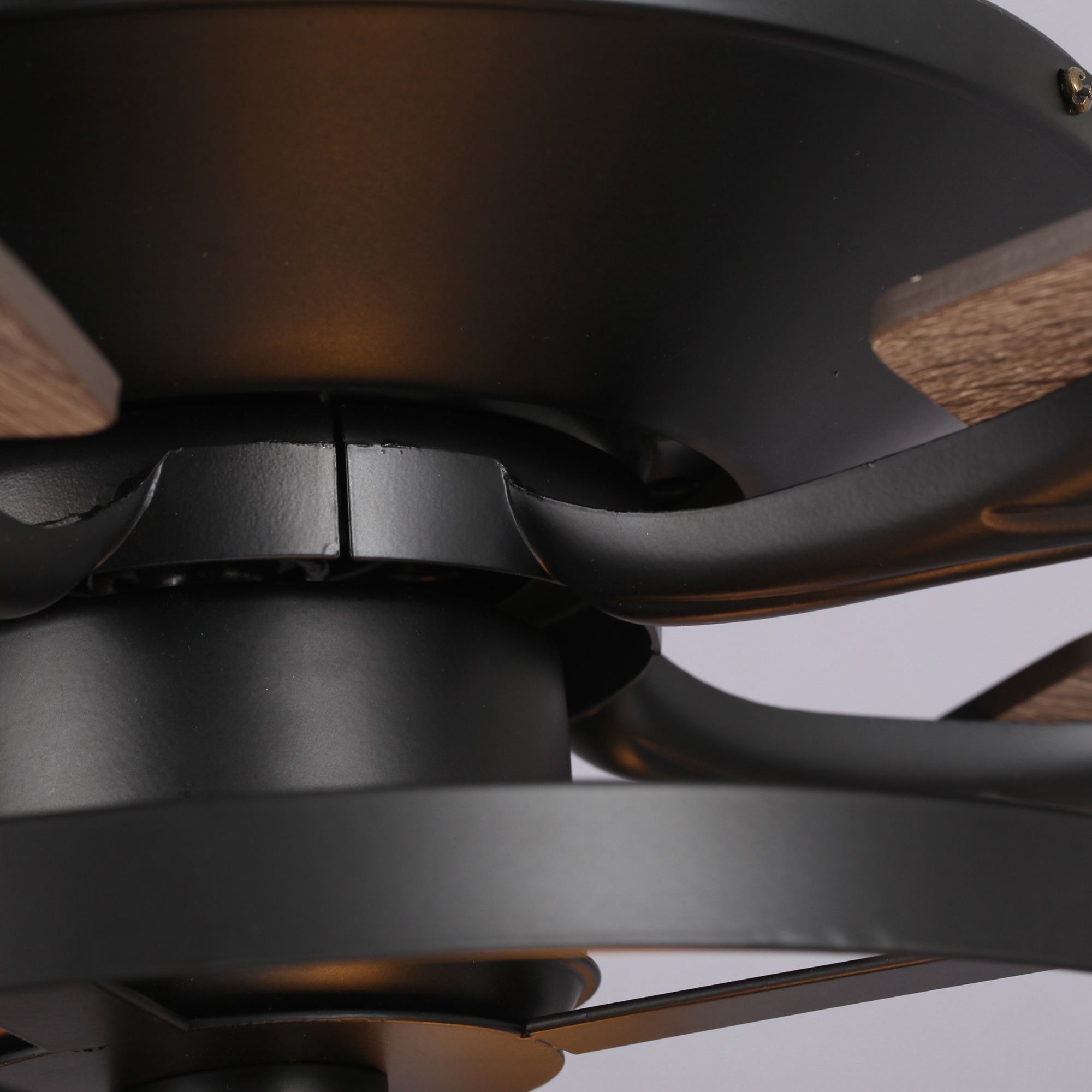 Close-up of modern black ceiling fan with wood accents and sleek metal blades