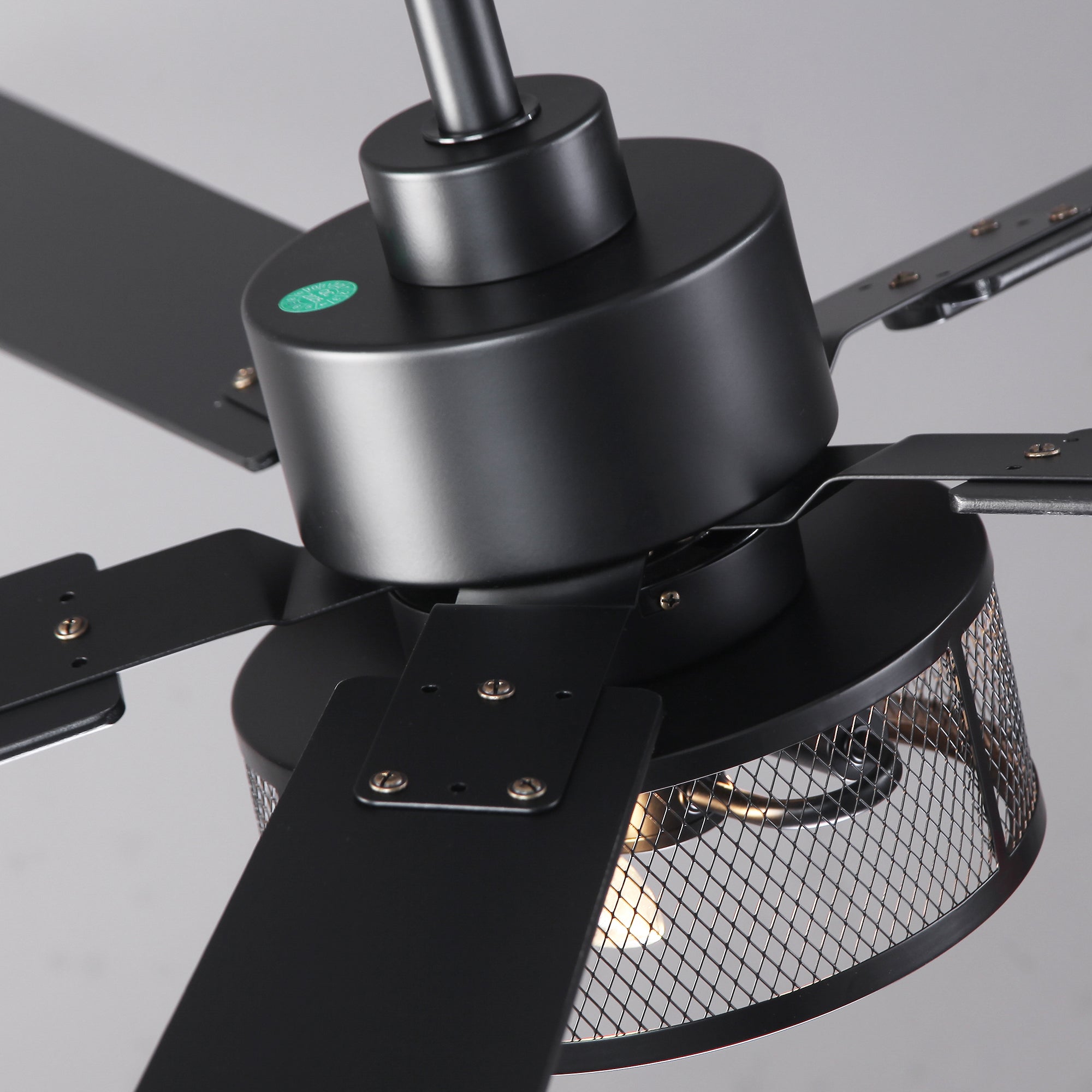 Modern black industrial ceiling fan with mesh metal light cover, close-up view