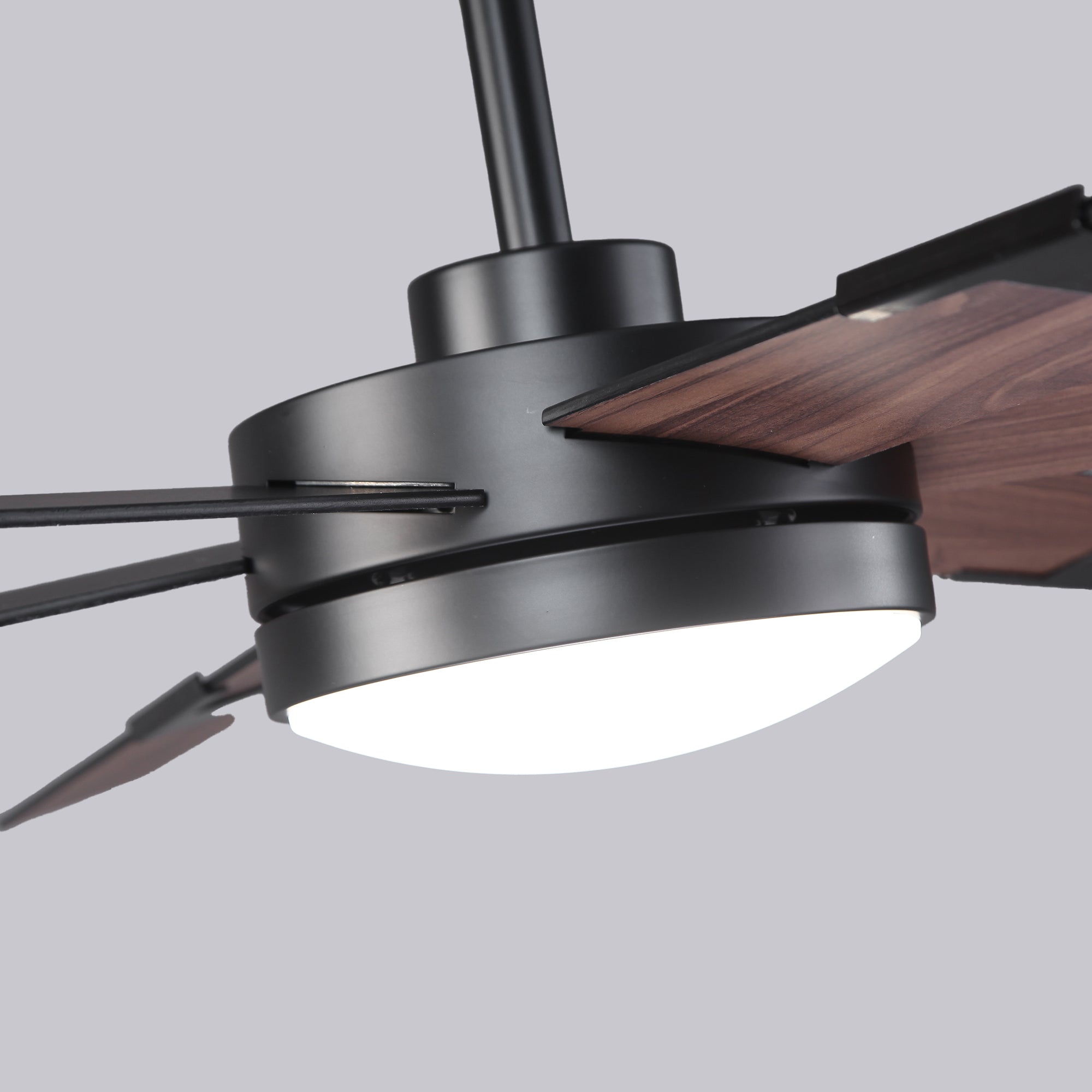 Modern ceiling fan with LED light, matte black finish, and wood blades, close-up view