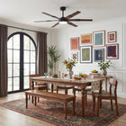 Modern ceiling fan with wood blades in a bright dining room with wooden table and art decor